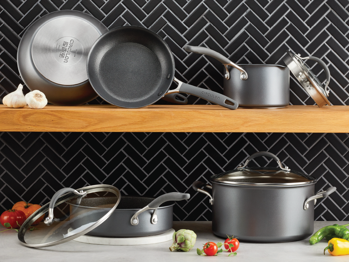 Collection of Circulon pots and pans sitting on a countertop and shelf. 