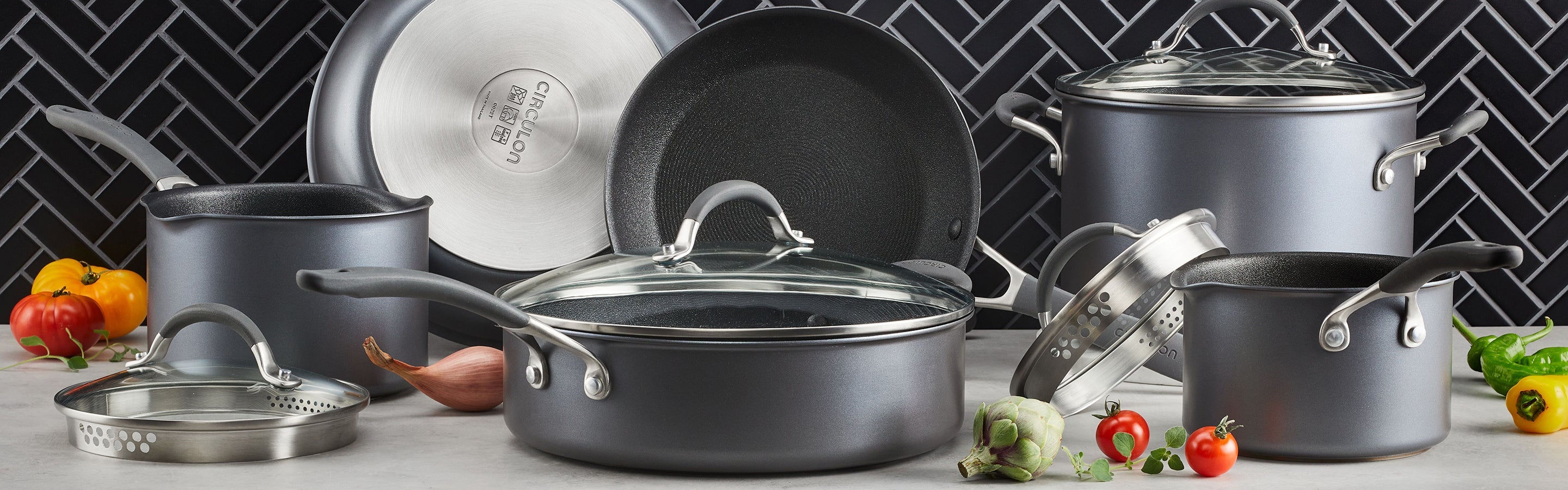 A stovetop scene with a brown pot cooking shrimp and vegetables, a matching pot on a wooden tray, utensils, and a small bowl of spices on a white countertop.