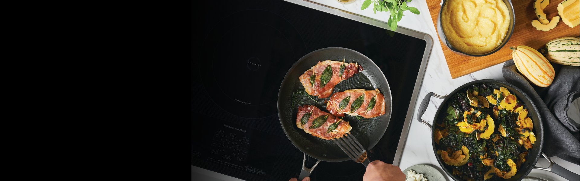 Person cooking prosciutto-wrapped chicken with sage in a pan on a stovetop; nearby are a dish of polenta, sautéed vegetables, and squash.