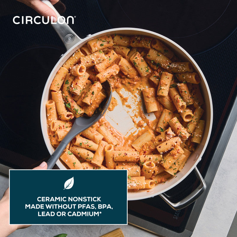 A hand stirs rigatoni in a Ceramic Nonstick 5-Quart Sauté Pan on the stove.