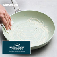 Hand wiping residue from a Ceramic Nonstick 2-Piece Skillet Set.