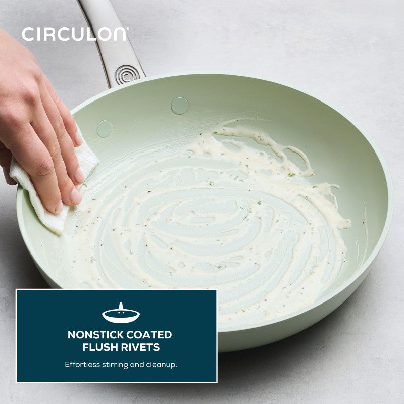 Hand wiping residue from a Ceramic Nonstick 2-Piece Skillet Set.