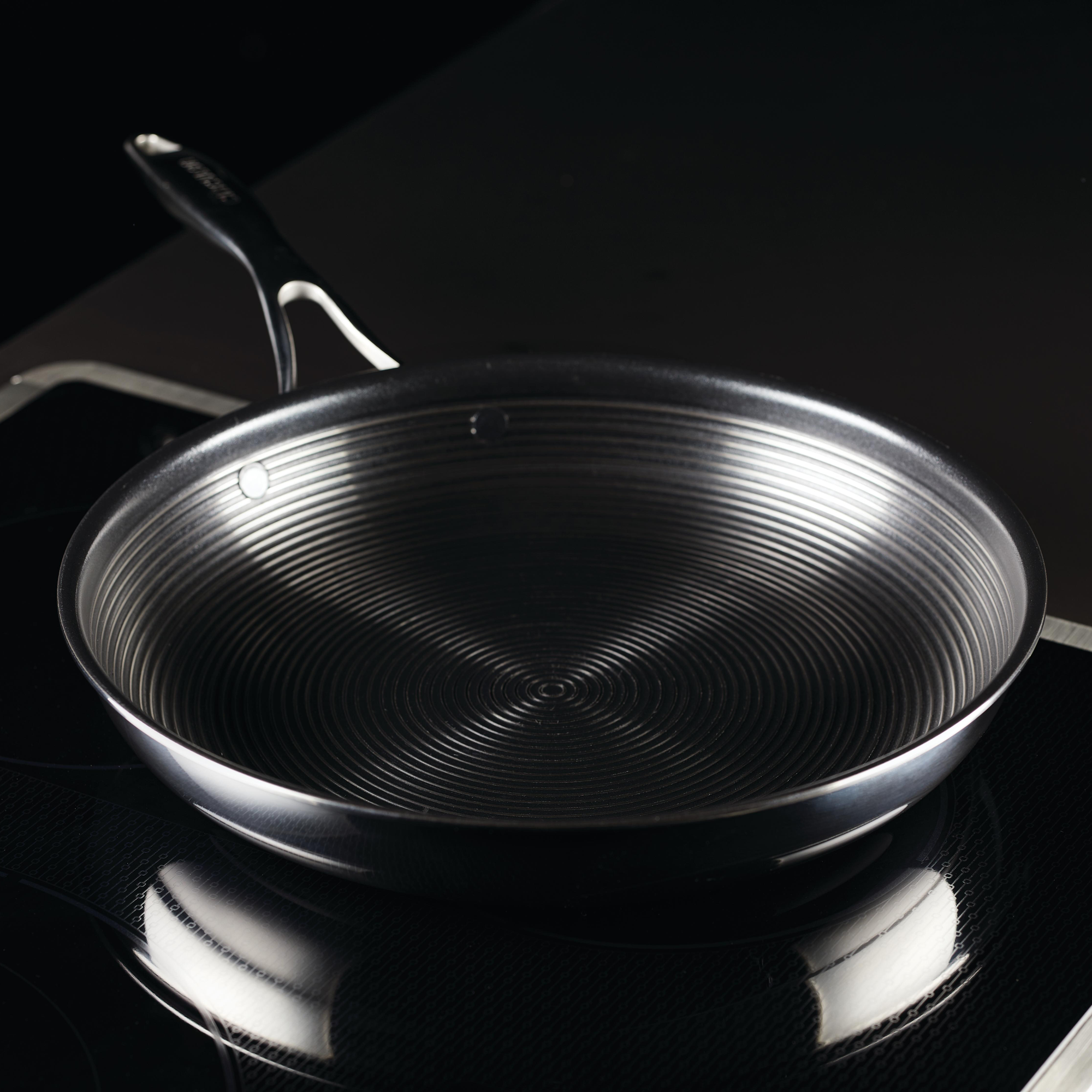 A stainless steel frying pan on a black stove.