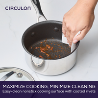 Hand cleaning a nonstick saucepan with a paper towel.