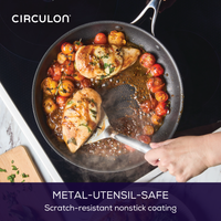 Hand cooking chicken and tomatoes in a nonstick frying pan on a stovetop.