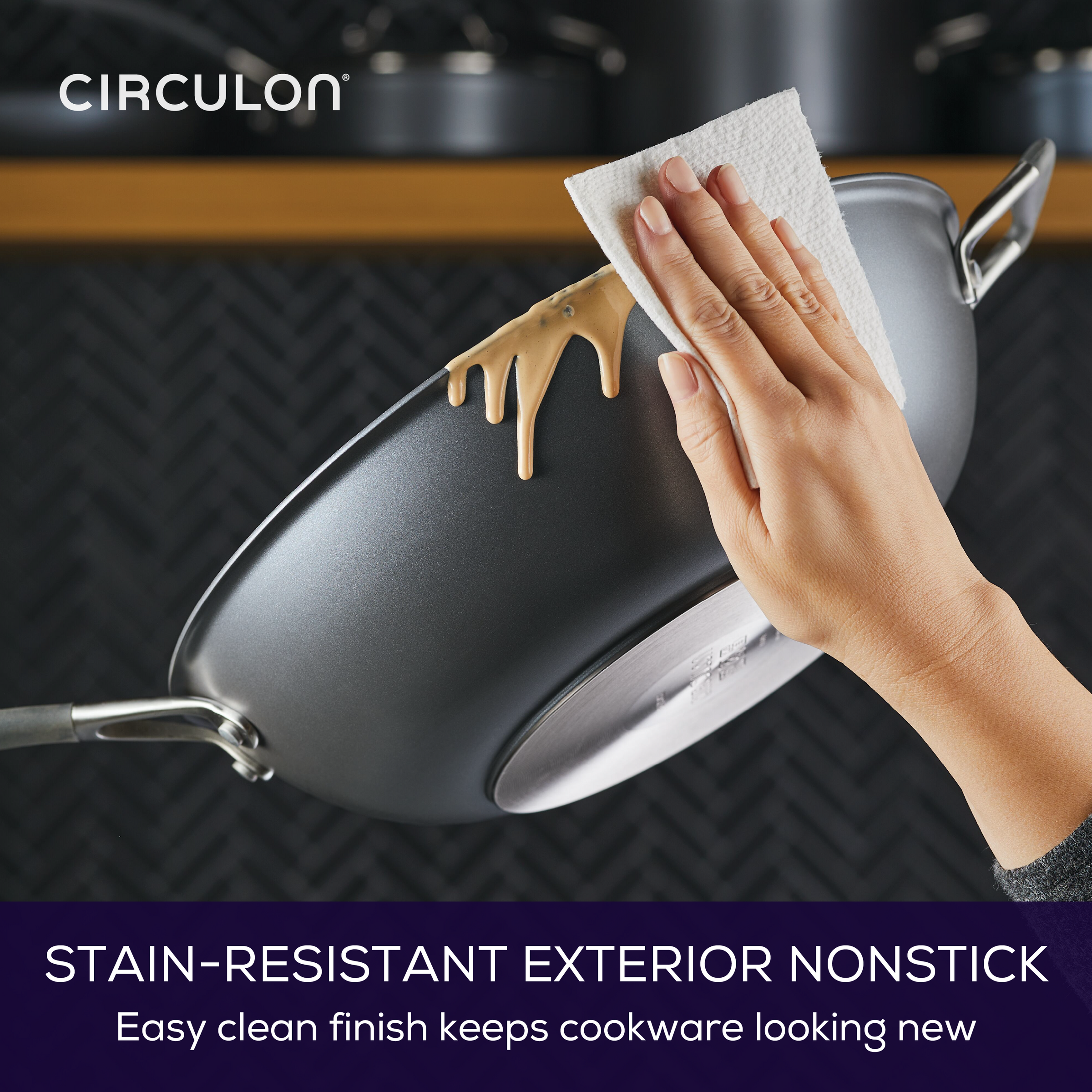 Hand wiping a 13" A1 ScratchDefense™ Nonstick StirFry pan with paper towel.