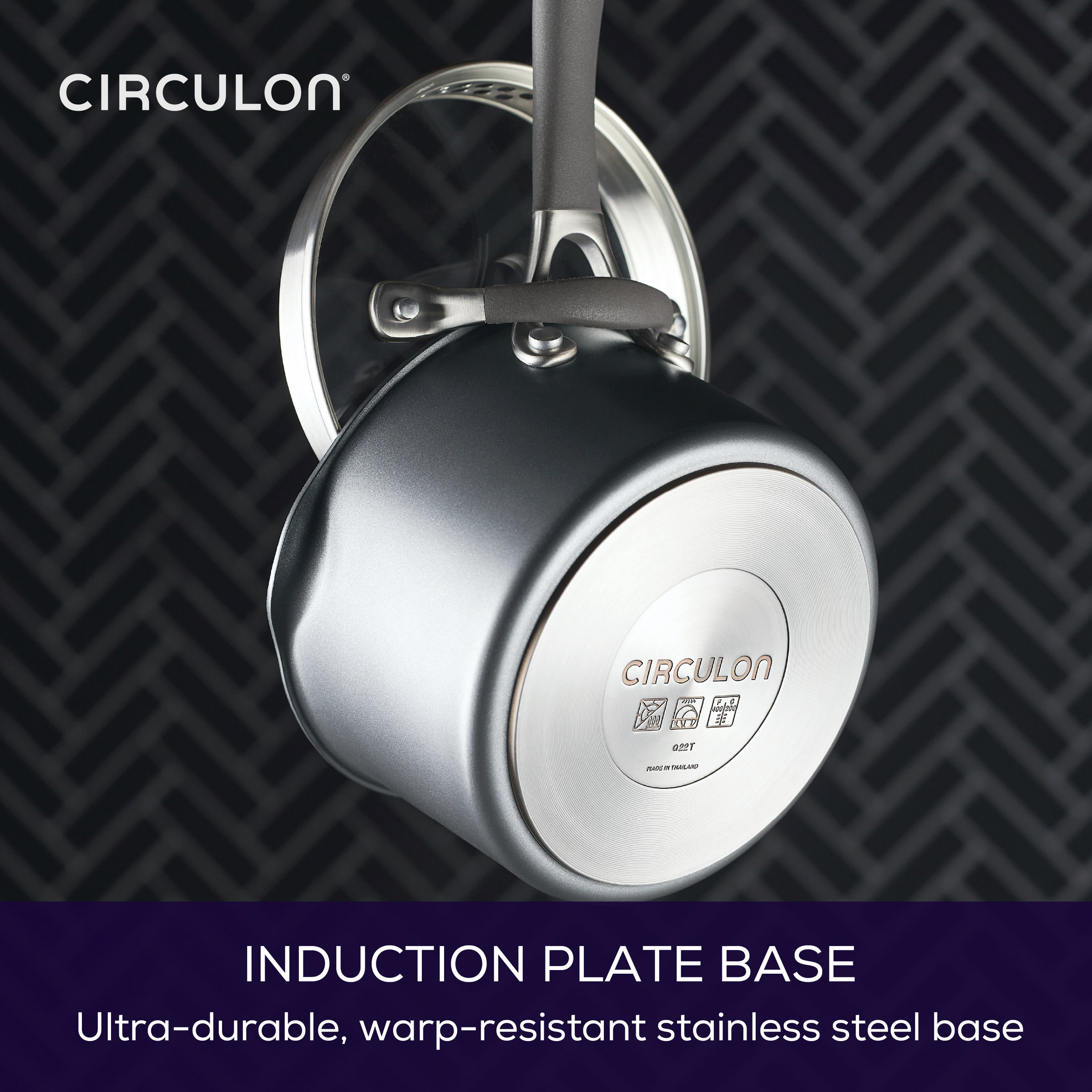 A shiny pot with an induction plate base hanging on a patterned background.