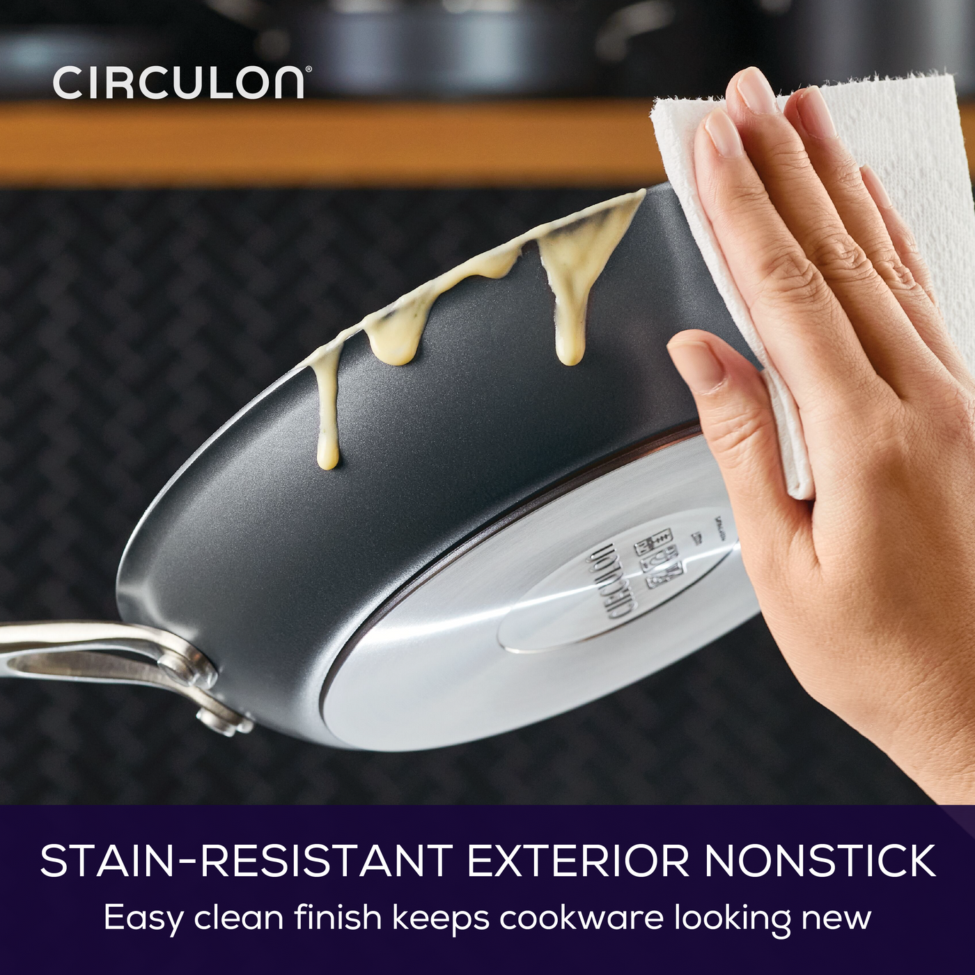 Person wiping a stain-resistant nonstick pan with a paper towel.