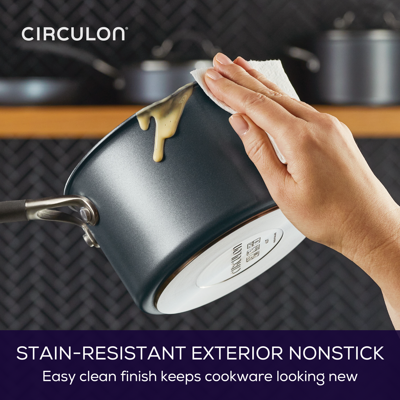 Hand cleaning a saucepan with a cloth, wiping off sauce.