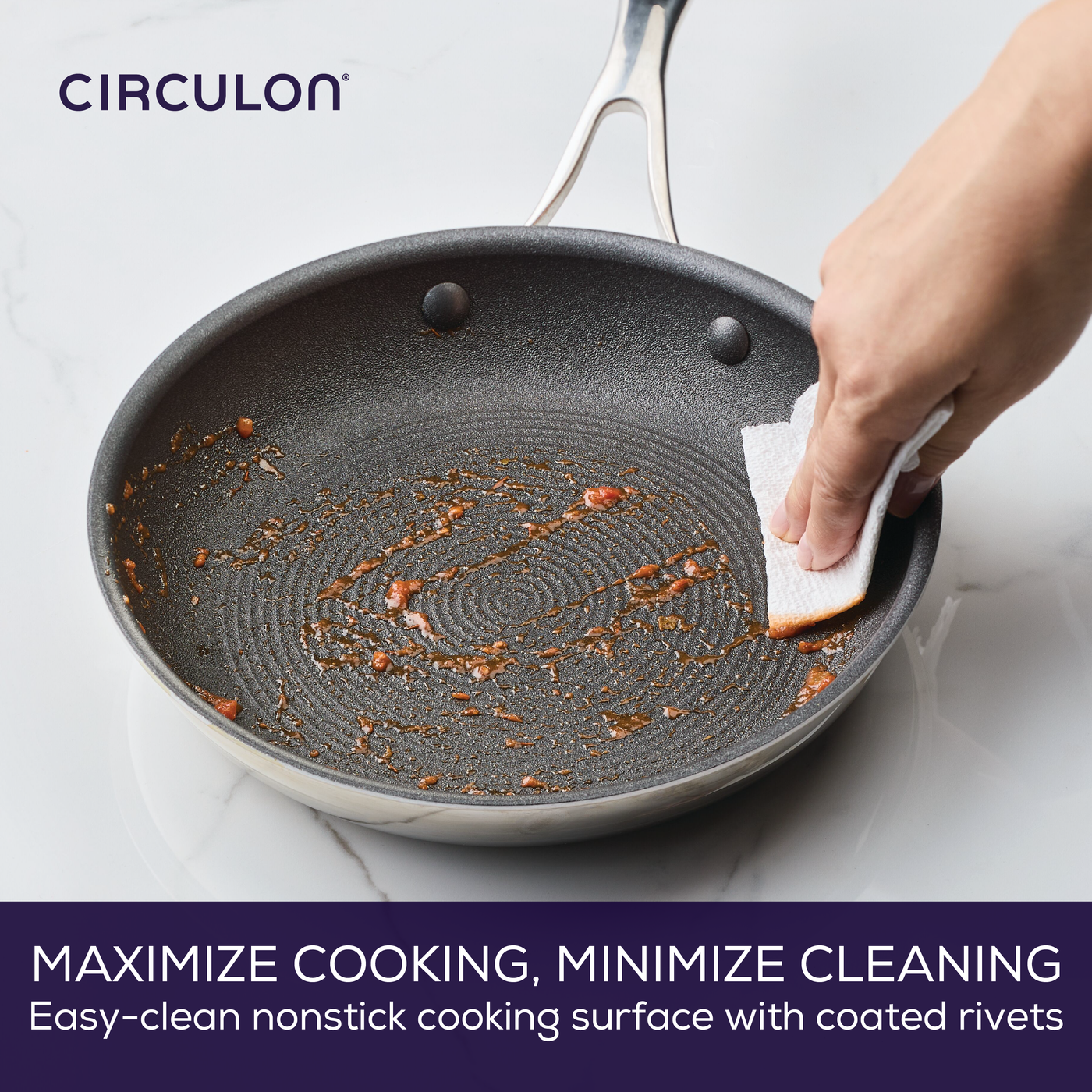 Person cleaning a nonstick frying pan with a paper towel.