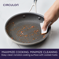 Hand cleaning a nonstick pan with a paper towel on a countertop.