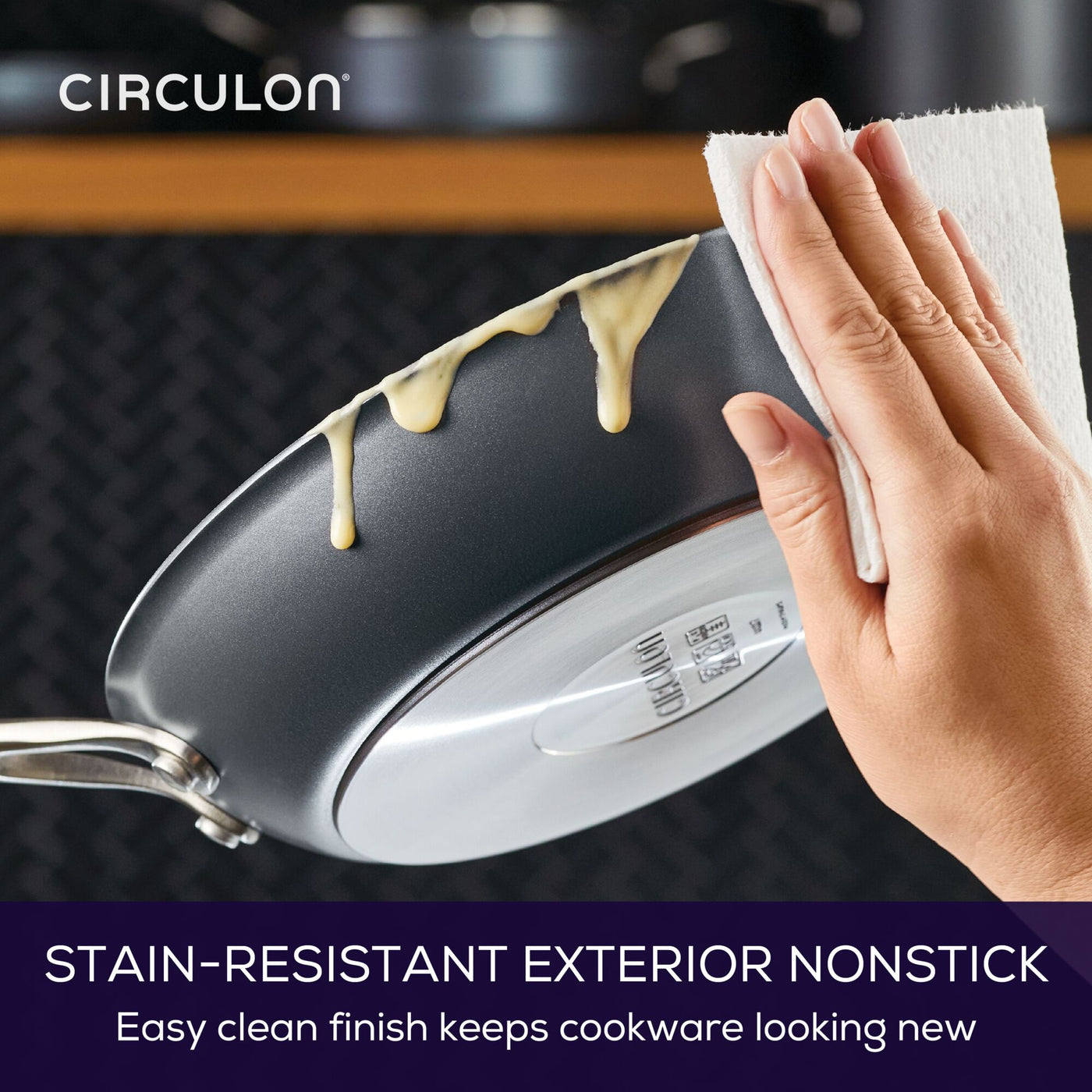 Person wiping a 12-Inch ScratchDefense™ pan; sauce drips down the side.