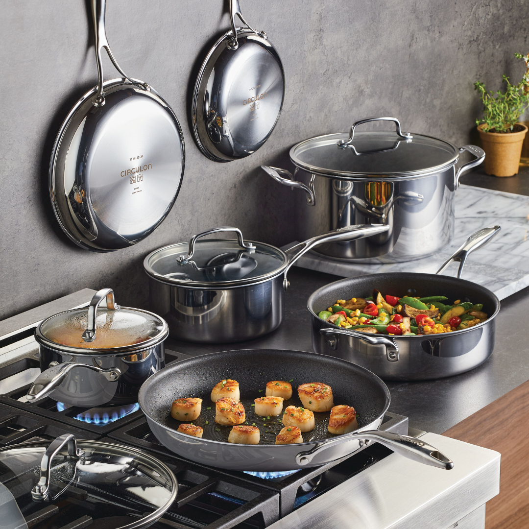 Cookware set on stove and wall; pots, pans, and food being prepared.