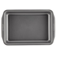 A rectangular pan from the 10-Piece Nonstick Bakeware Set, featuring a textured bottom and constructed from heavy gauge steel for enhanced warp resistance, seen from an overhead perspective.